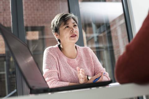 Vrouw luistert naar man met laptop op bureau