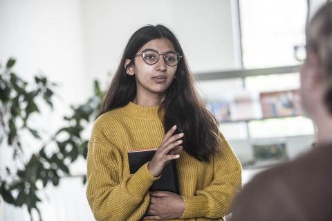 Jonge vrouw vertelt iets aan andere persoon