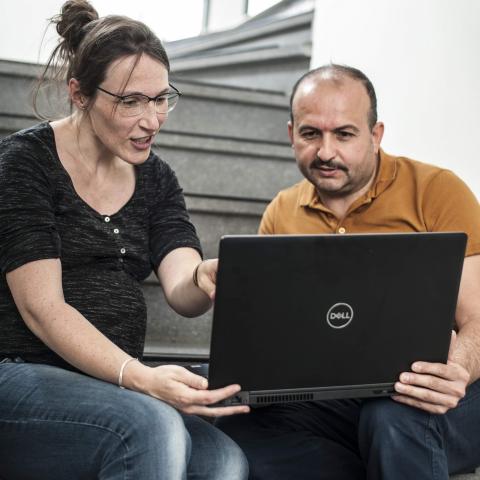 Vrouw legt iets uit aan man op computer