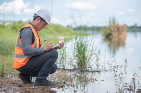 Man met helm controleert waterstaal bij vijver
