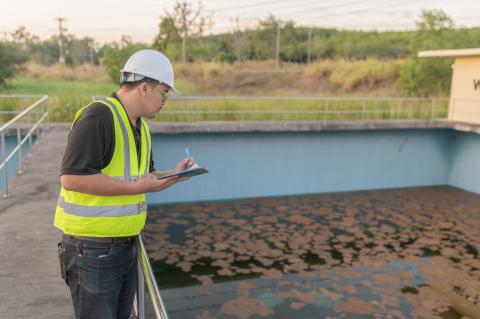 Man met helm en notablok checkt vervuild water